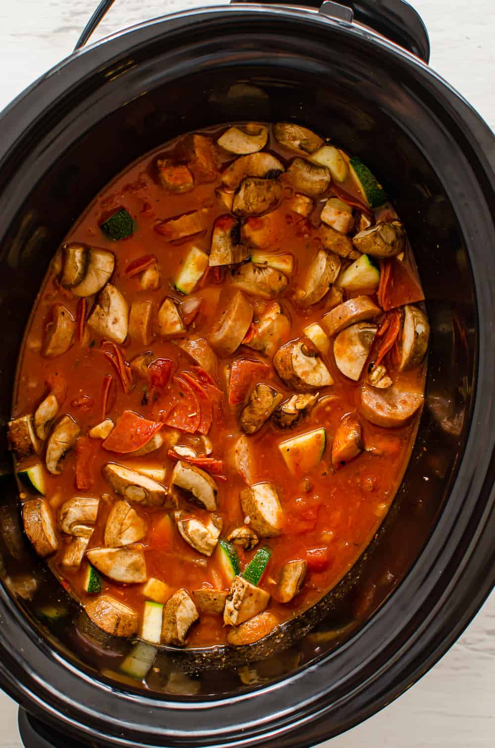 Pizza soup ingredients in a crockpot.