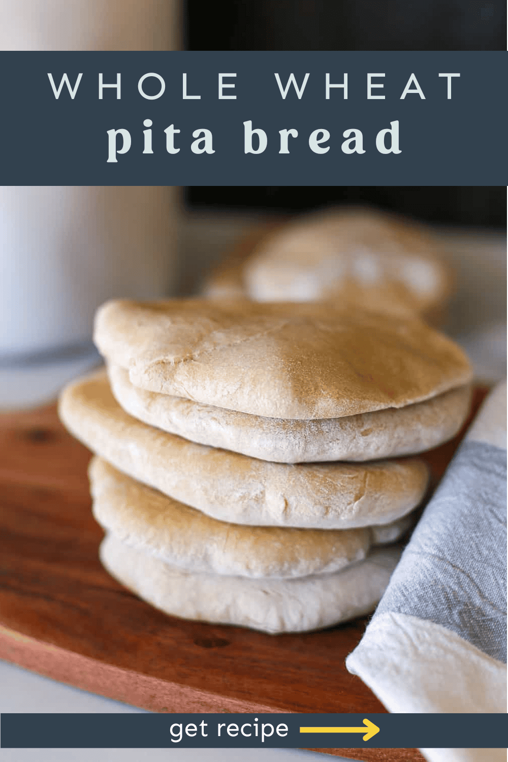 Homemade pita bread stacked up on a wooden cutting board.