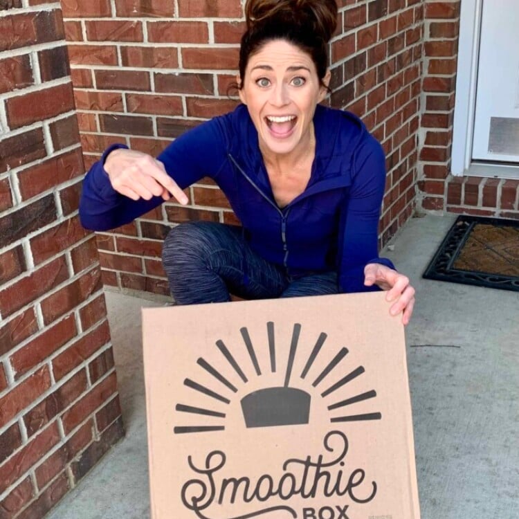 Rachel on her front porch excited and pointing to her Smoothie Box that was just delivered.