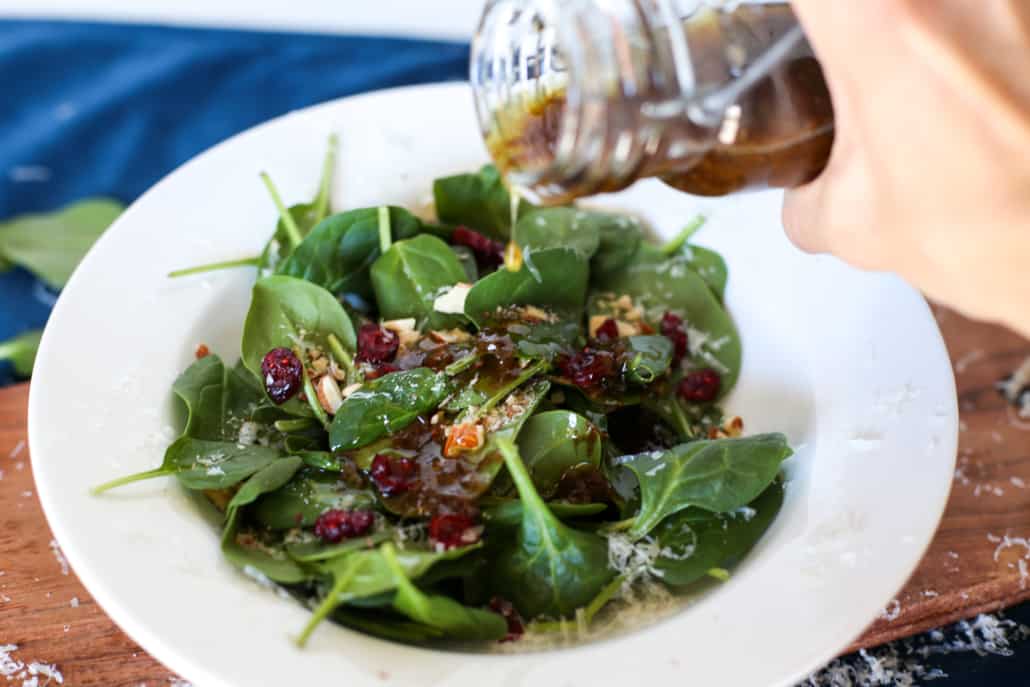 Parmesan Balsamic Vinaigrette being poured over a spinach salad