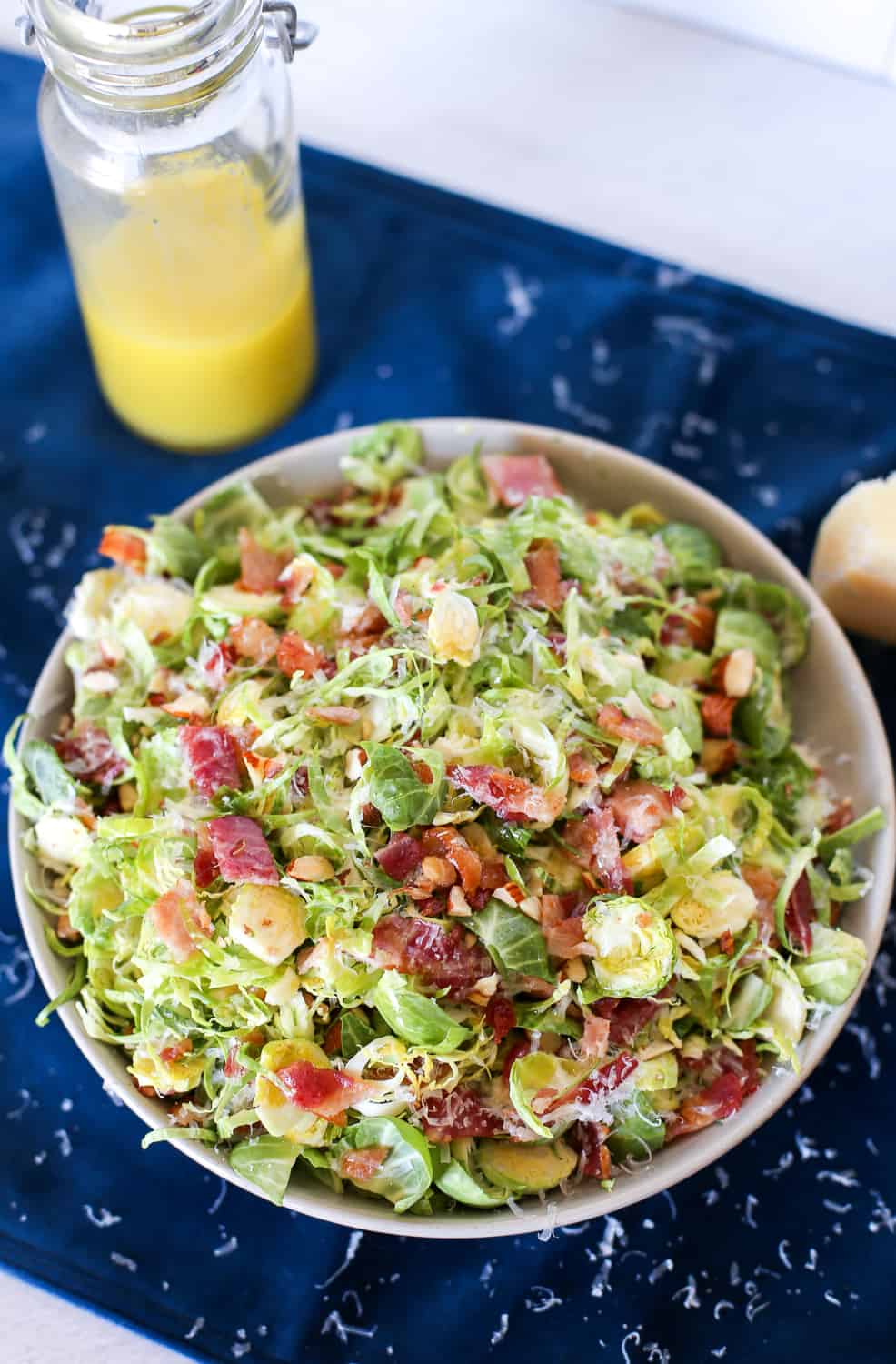 Shaved Brussels sprout salad in a white bowl with citrus dressing in the background.