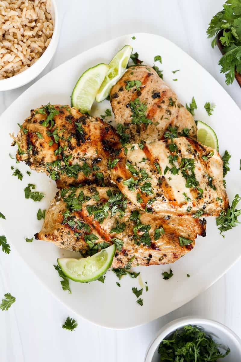 Grilled cilantro lime chicken breasts on a plate with chopped cilantro on top.