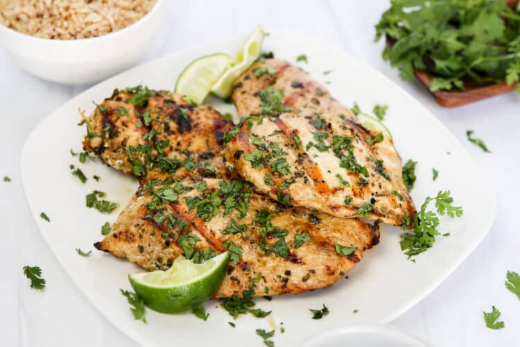 cilantro lime marinated chicken breasts that have been grilled on a plate with brown rice on the side