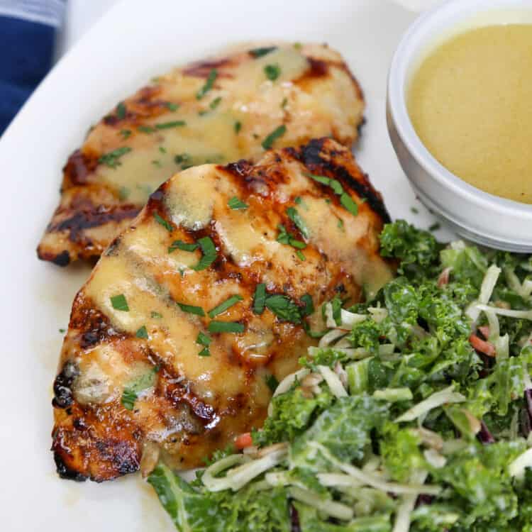 Grilled honey mustard chicken on a plate with salad and sauce.