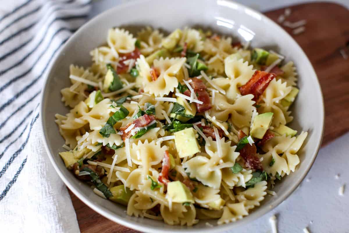 Avocado pasta with basil and bacon in a small bowl.