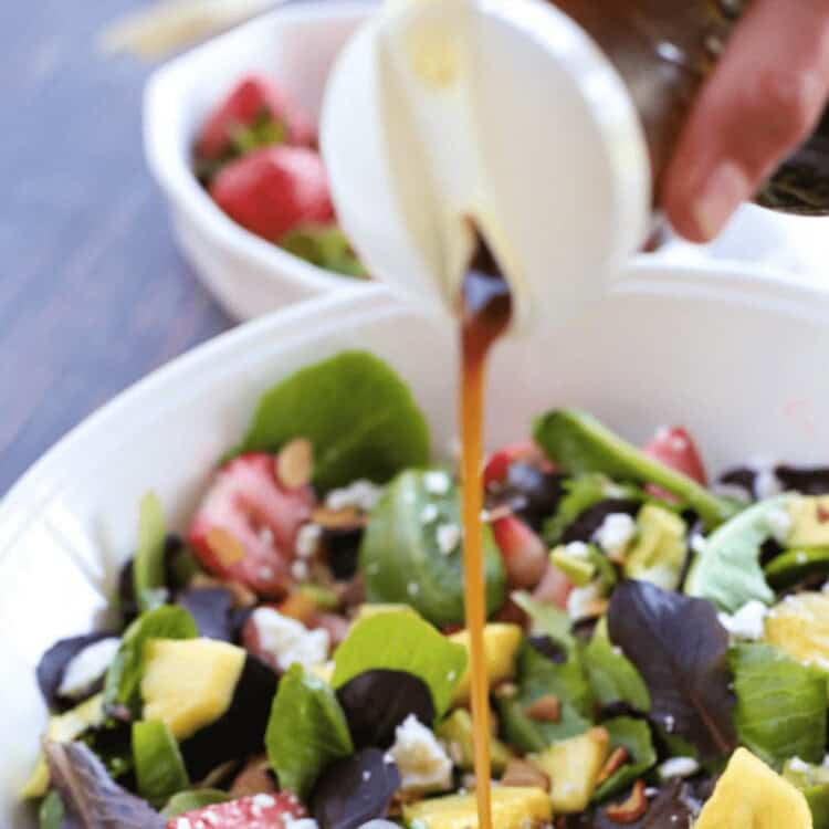 Honey balsamic dressing being poured onto a salad.