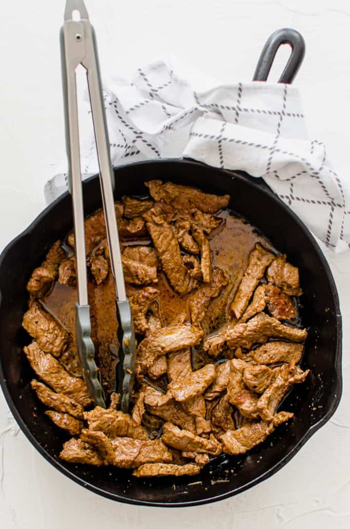 sautéed steak in a cast iron skillet with fajita marinade