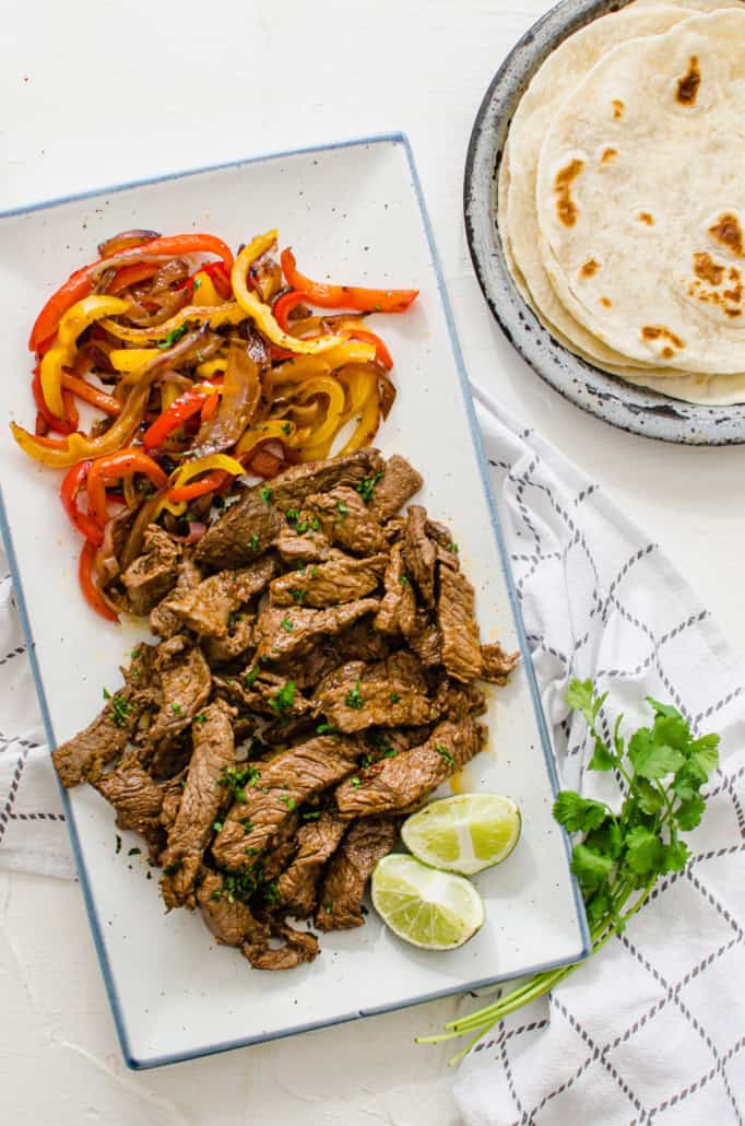 vertical shot of a serving platter with fajita peppers, onions, and steak