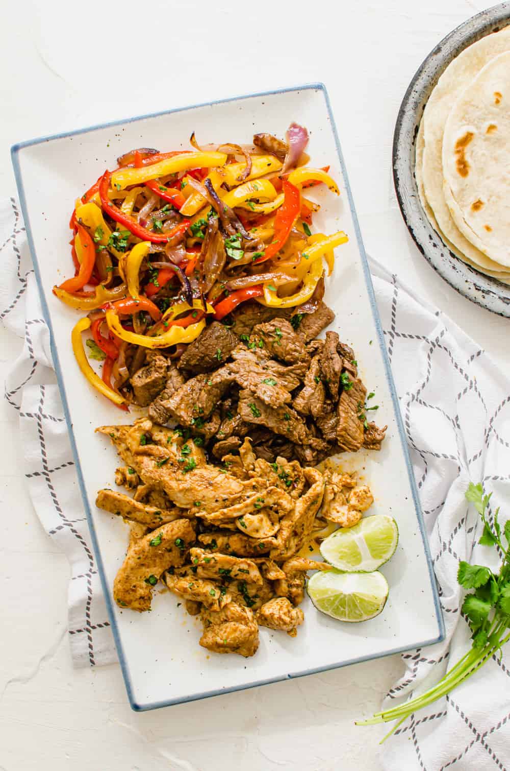 vertical overhead shot of a serving platter with fajita veggies, steak, and chicken