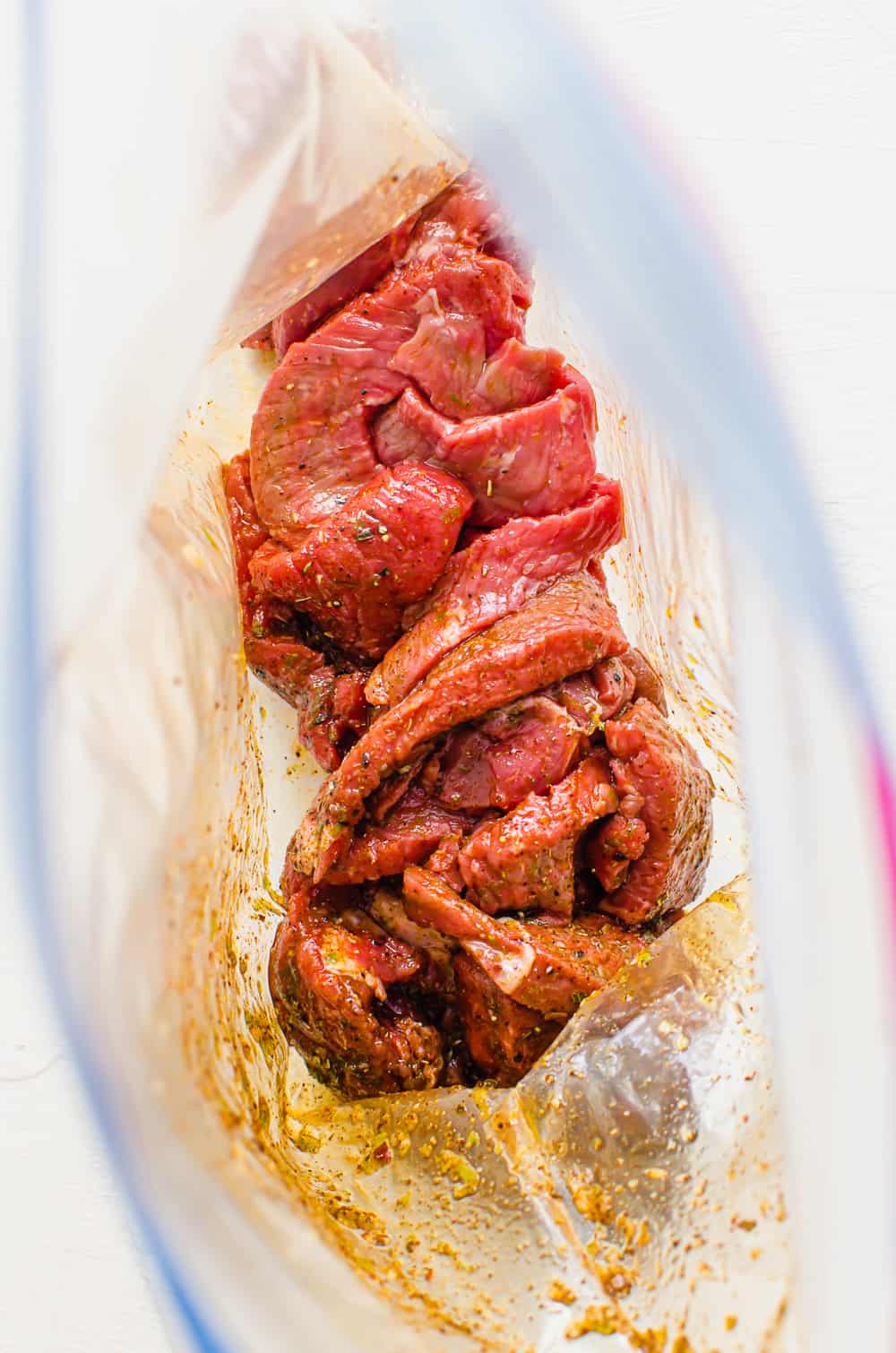 A freezer bag with fajita marinade and thinly sliced steak.