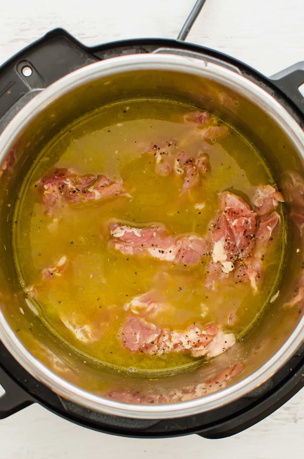 Broth and chicken thighs in the Instant Pot for chicken and dumplings.