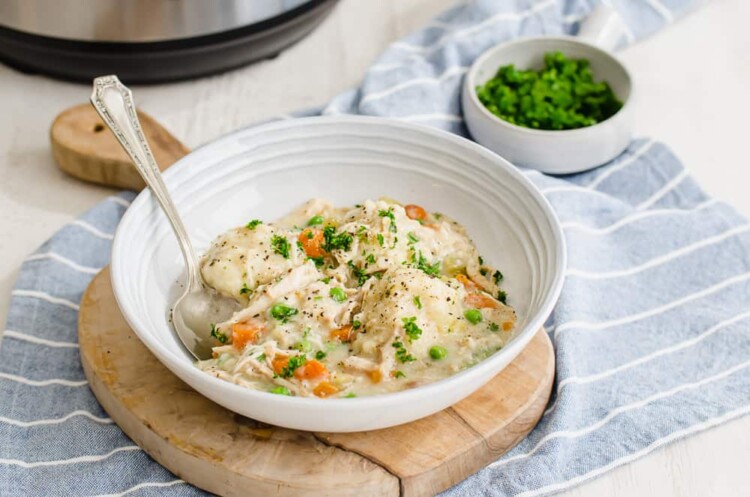 A bowl of chicken and dumplings in front of an Instant Pot.