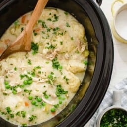 Crock Pot chicken and dumplings ready to serve with fresh chopped parsley.