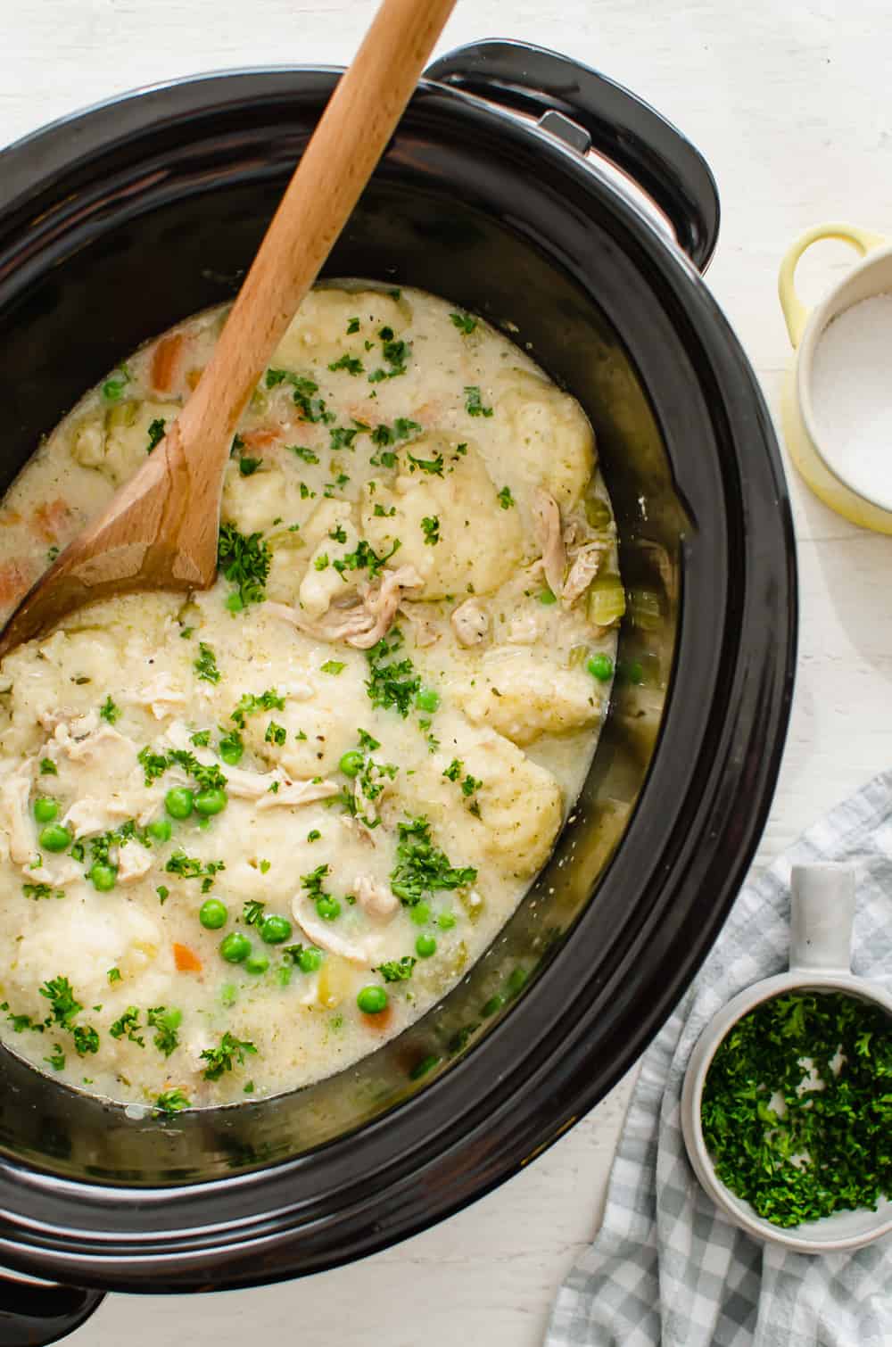 Crock pot chicken and dumplings ready to be served with chopped fresh parsley on top.