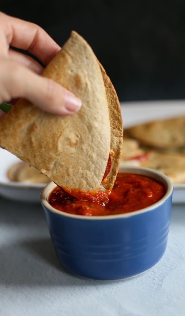 A pizza quesadilla being dipped in marinara