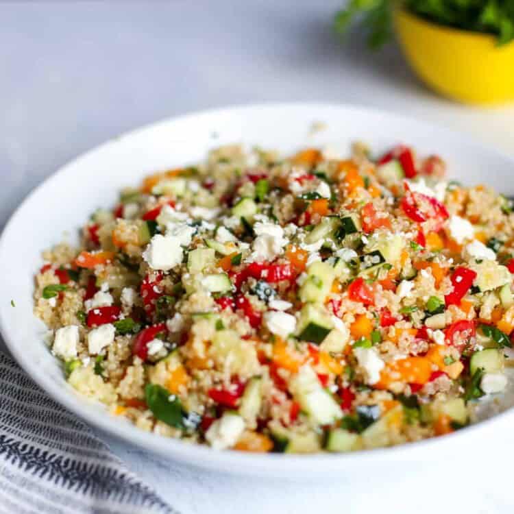 Quinoa tabbouleh in a white bowl with a serving spoon next to it.