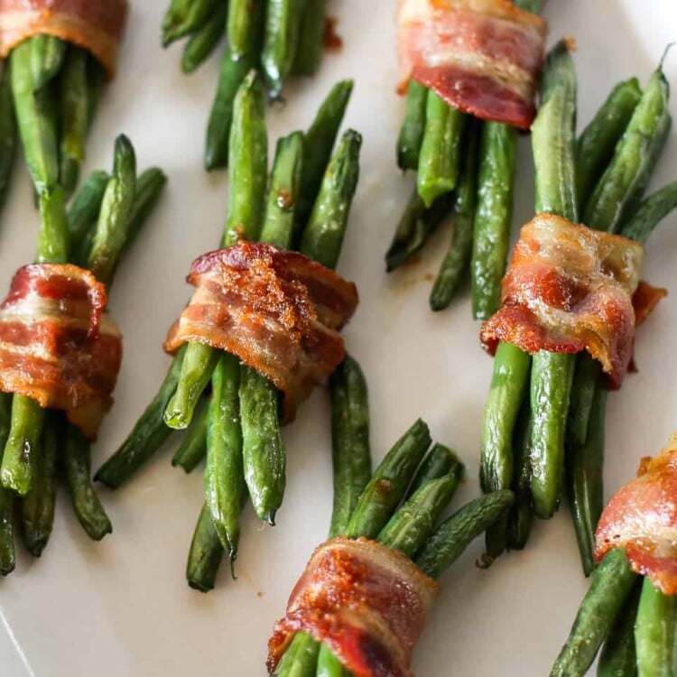 Green beans wrapped in bacon sitting on a baking sheet with parchment paper.
