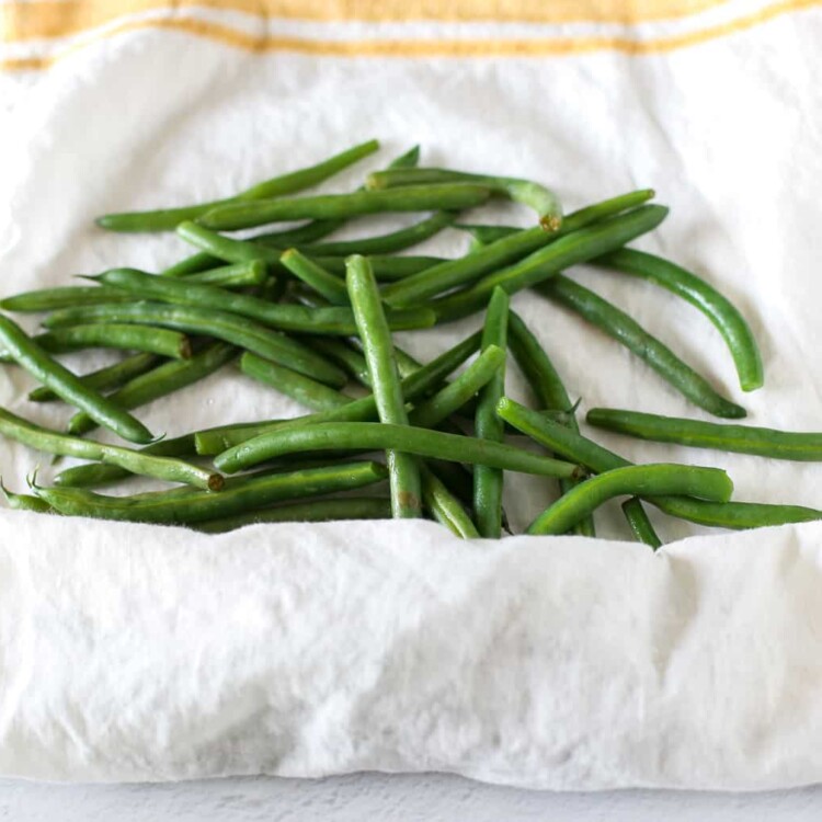 Par cooked green beans being wrapped in a towel to dry.