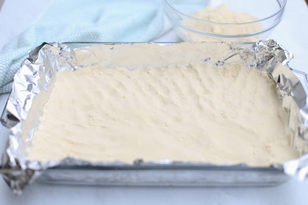 Shortbread crust being pressed into a 9x13 dish