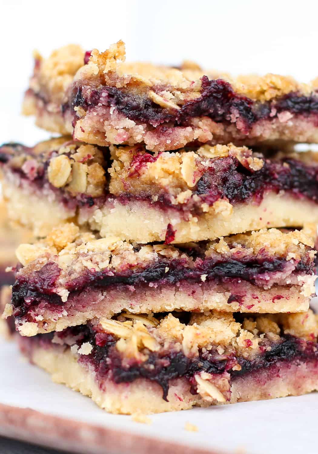 Blueberry crumble bars stacked on top of each other with blueberry filling spilling out.