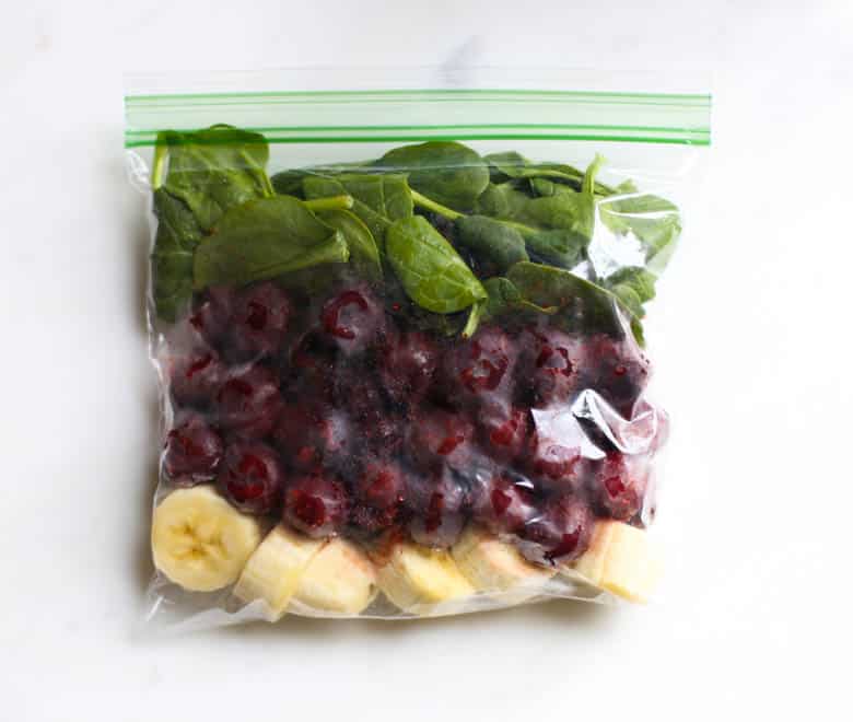 Chocolate covered cherry smoothie ingredients layered in a freezer-safe bag to make a smoothie pack for the freezer.
