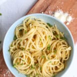 A serving of butter noodles in a blue bowl on a wooden cutting board.