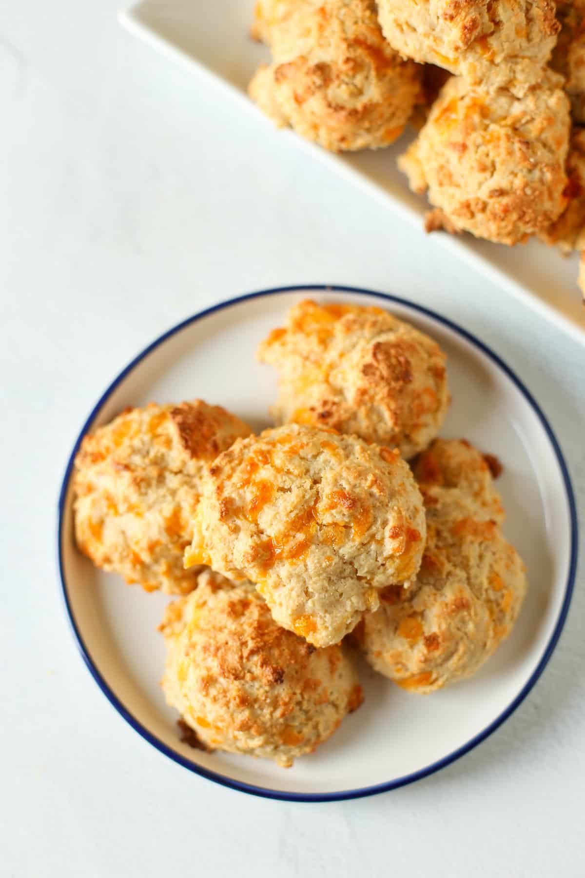 Homemade cheddar biscuits stacked on a plate.