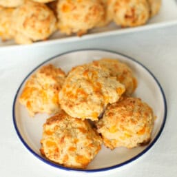 Cheddar biscuits on a white platter to serve.