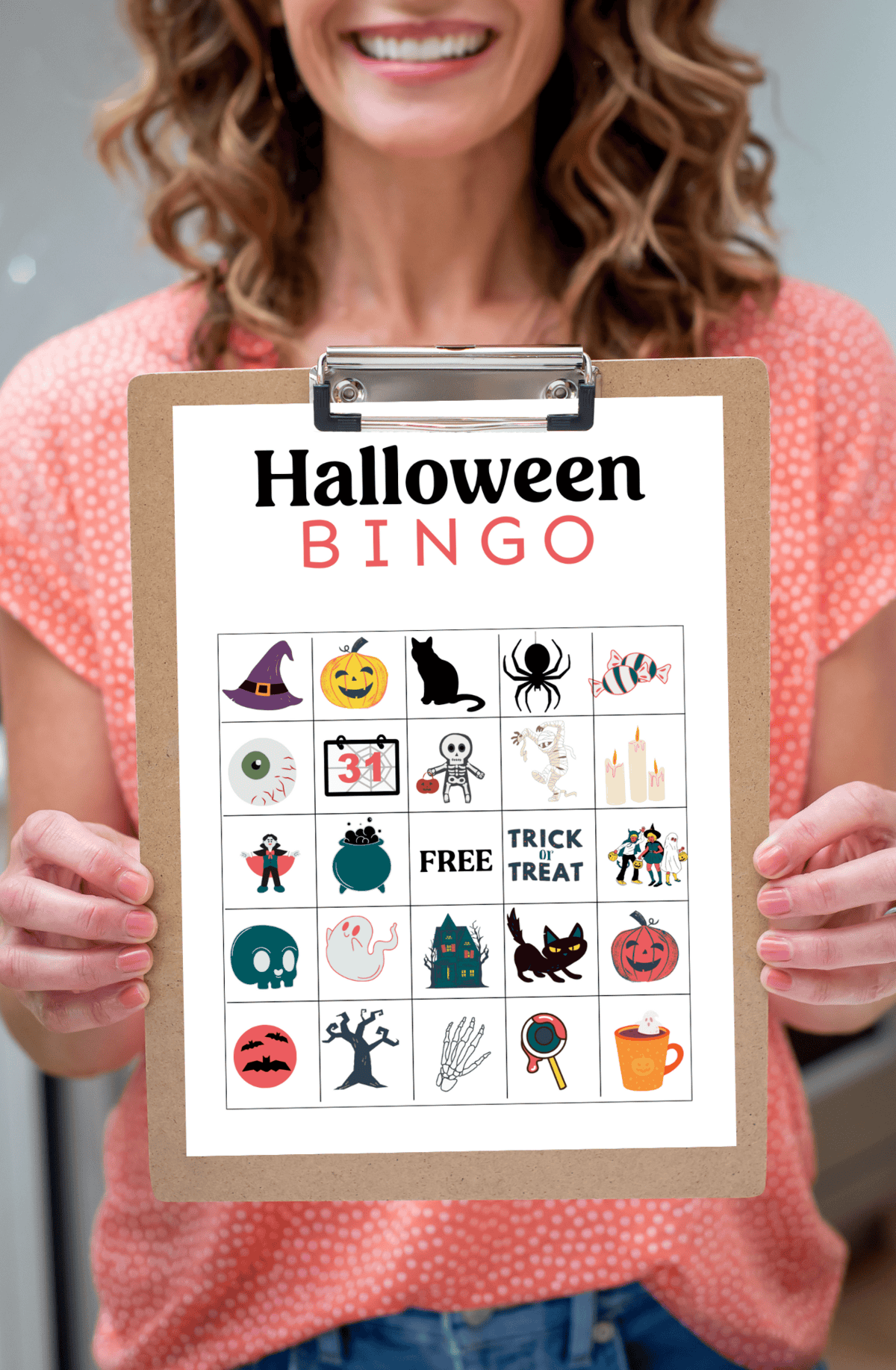 Woman holding a Halloween bingo card on a clipboard.