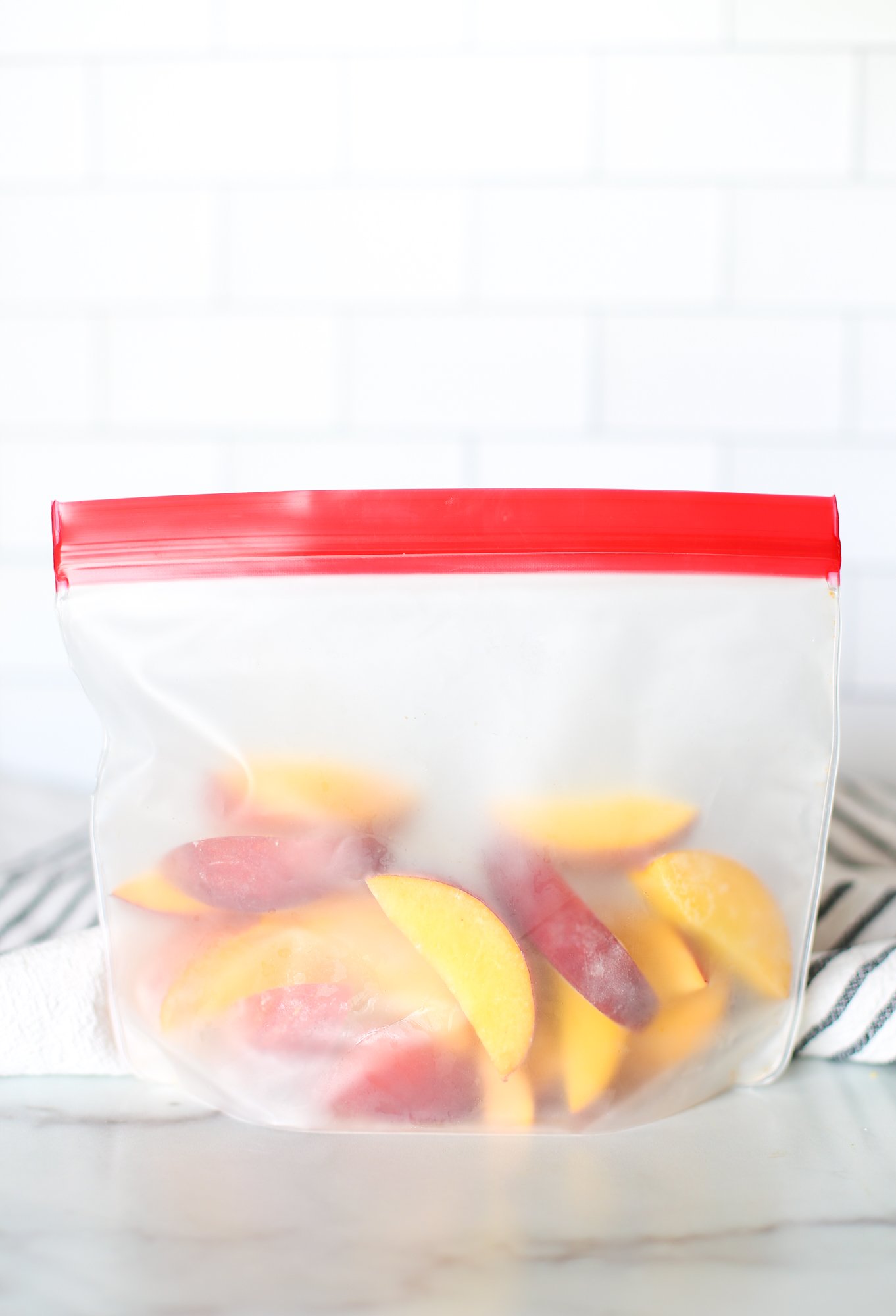 Frozen peaches in a reusable freezer bag on the counter.