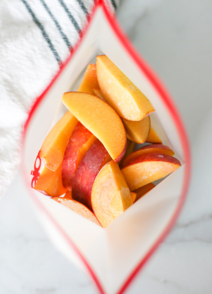 Overhead shot of frozen peaches in a reusable freezer bag.