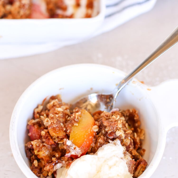 peach crisp in bowl with spoon