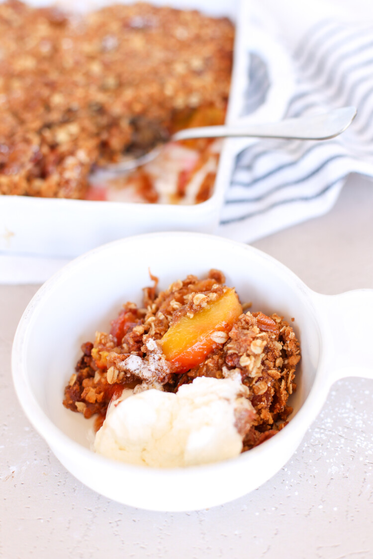 Bowl with a serving of Peach Crisp and vanilla ice cream.