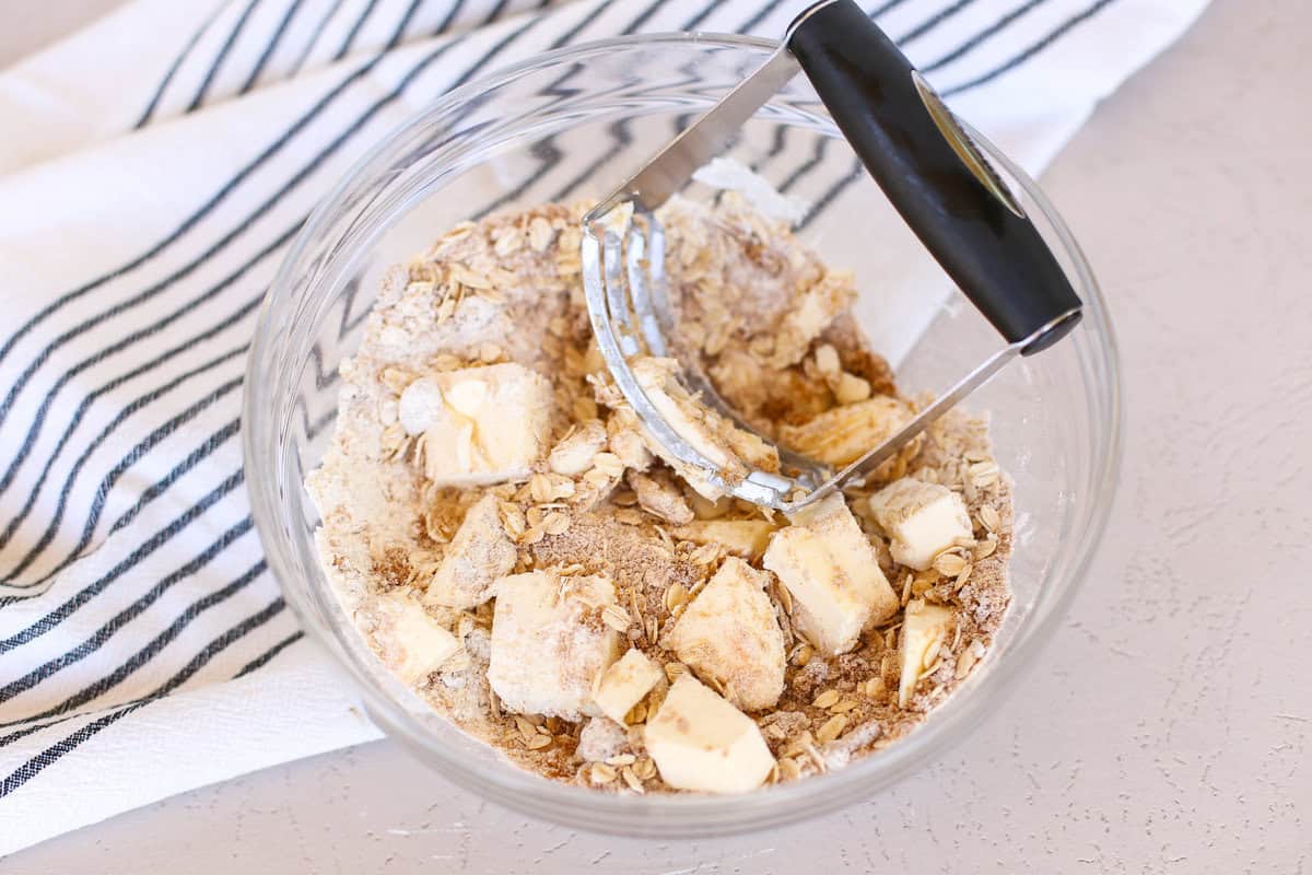 Cutting in butter to dry ingredients with a pastry cutter for peach crisp.