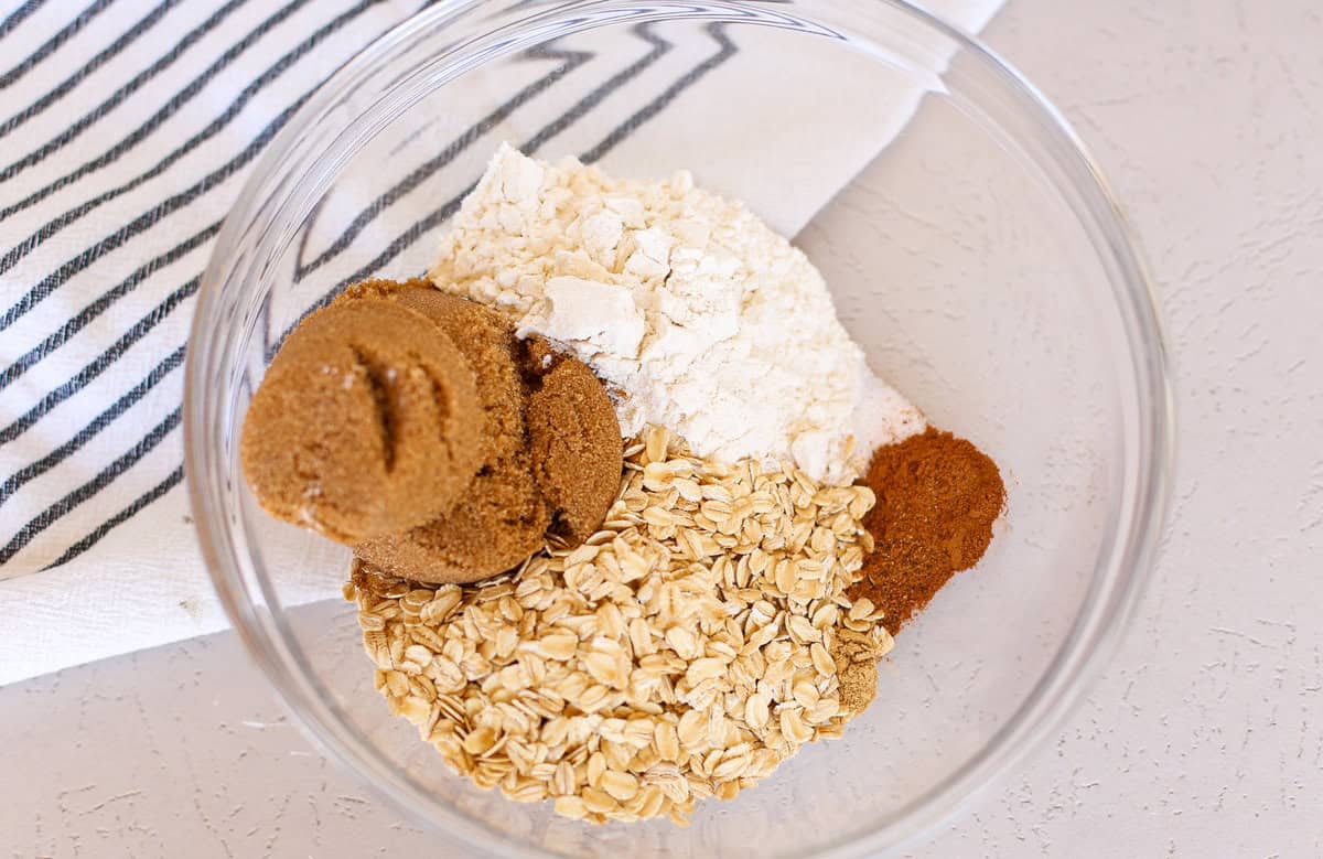 Dry ingredients for peach crisp in a glass mixing bowl.