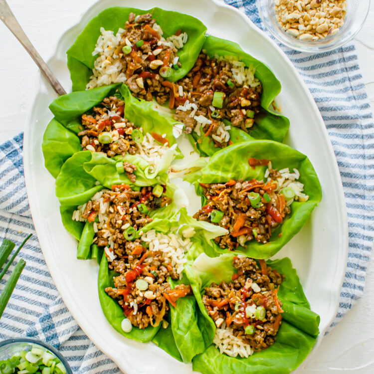 Chicken lettuce wraps laying on a white serving platter.