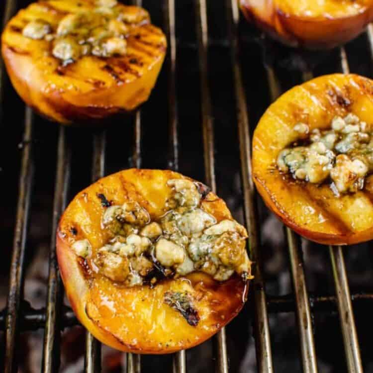 grilled peaches with gorgonzola, balsamic, and honey on top of each one on a grill