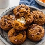 Healthy Pumpkin Chocolate Chip Muffins on a plate with the one on top split in half with butter in it.