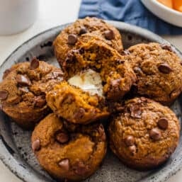 Healthy Pumpkin Chocolate Chip Muffins on a plate with the one on top split in half with butter in it.