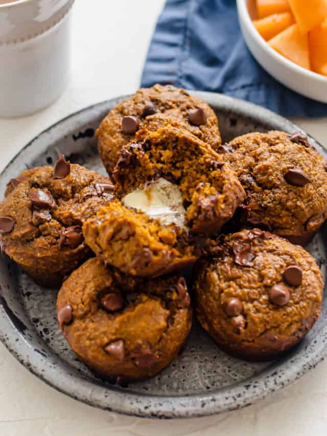 Healthy Pumpkin Chocolate Chip Muffins on a plate with the one on top split in half with butter in it.