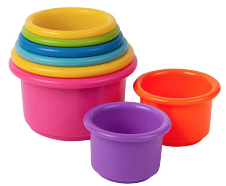 Stacking color cups made of hard plastic with most of them in the stack, but the top two are sitting next to the stack.
