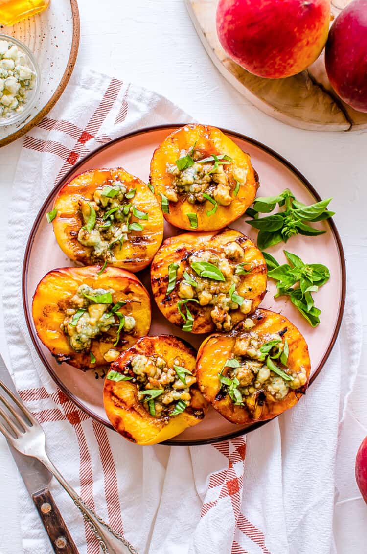 Grilled peach halves with feta cheese, and balsamic drizzle lined up on a serving platter.