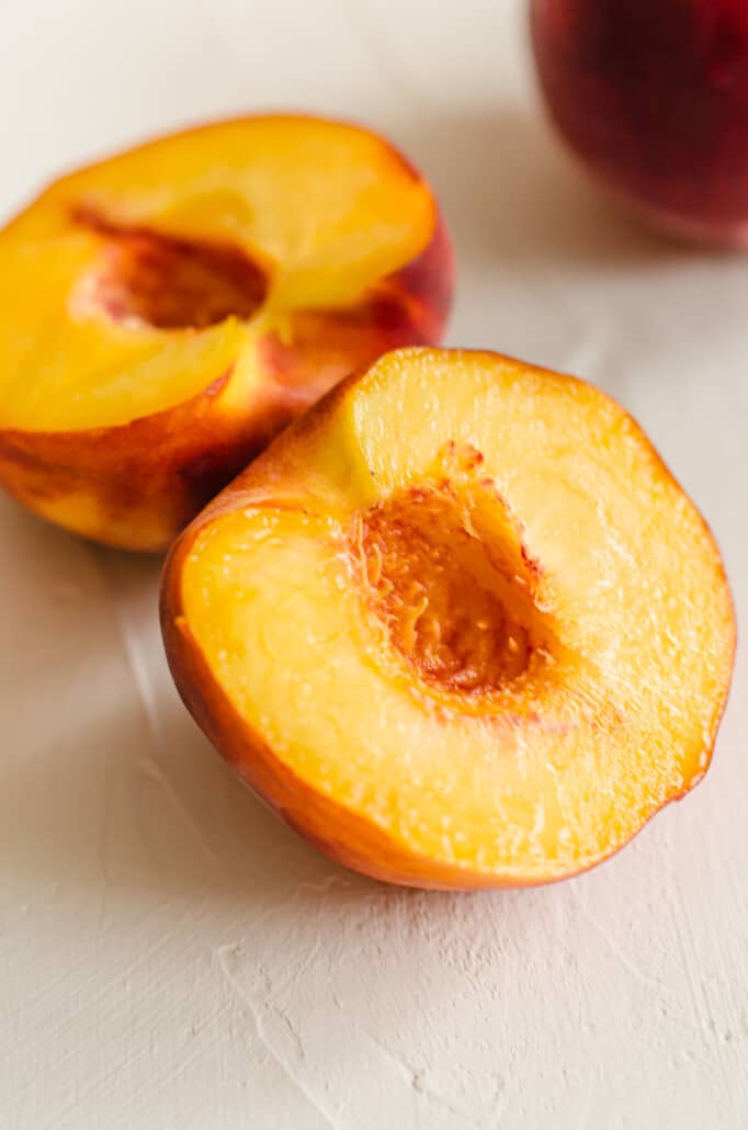 peaches pitted and cut in half on a counter
