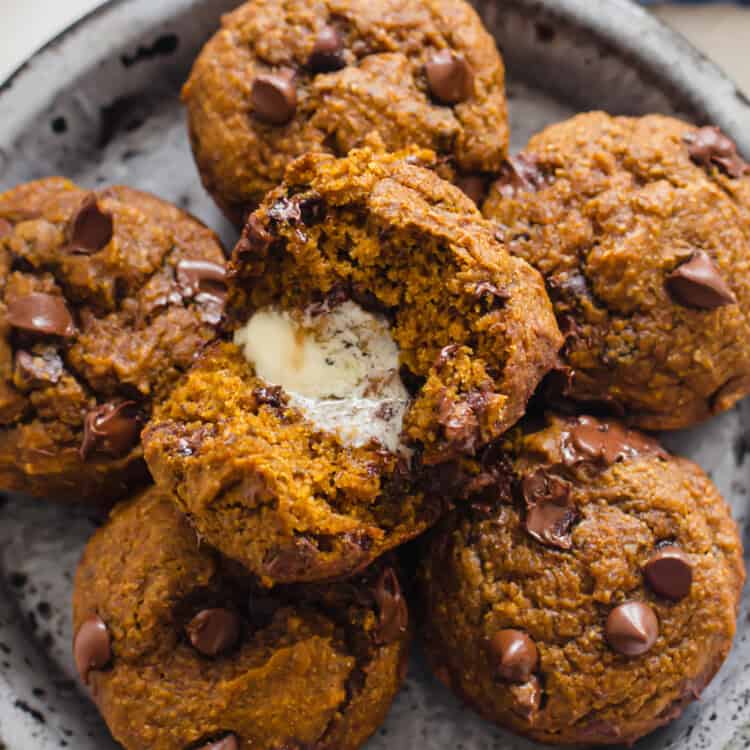 Pumpkin chocolate chip muffins stacked on a plate.