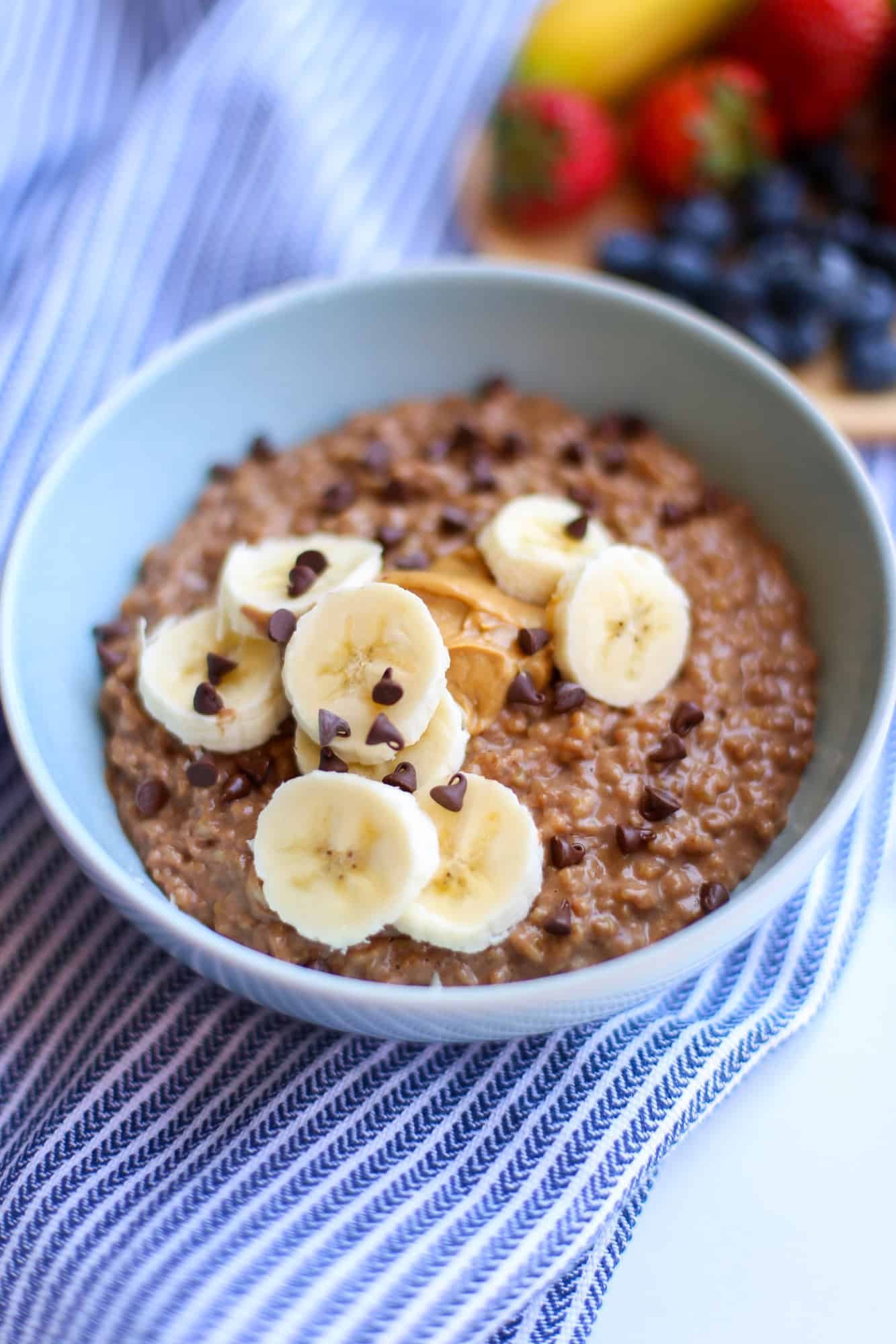 Peanut Butter Cup steel cut Oatmeal in a blue bowl with banana and chocolate chips topping. 