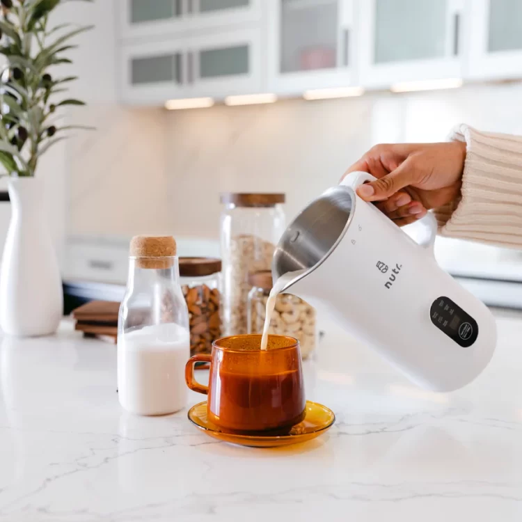 A person pour almond milk from a Nutr machine.