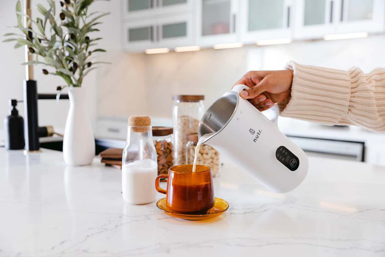 A Nutr machine pouring homemade almond milk into a mug.