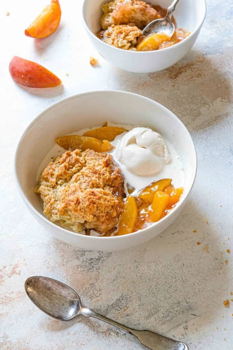 Bowl of peach cobbler with vanilla ice cream.