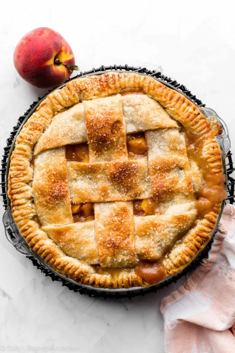 Peach pie with lattice crust in a black pie pan.