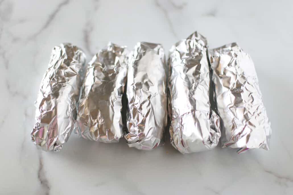 Burritos wrapped in foil ready for the freezer or for the oven.
